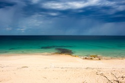 A calm Ocean Beach Bunbury Western Australia on a cloudy afternoon in summer create a scenic sea scape with an ominous dark grey cumulonimbus sky threatening showers.