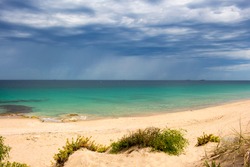 A calm Ocean Beach Bunbury Western Australia on a cloudy afternoon in summer create a scenic sea scape with an ominous dark grey cumulonimbus sky threatening showers.