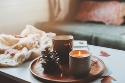 cozy autumn or winter morning at home. Still life details with cup of tea, candle, sketch book with herbarium and warm sweater. Scandinavian hygge concept