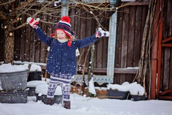 happy little girl having fun and throwing snow in winter snowy garden