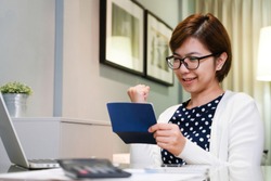 Beautiful Asian female smiling in celebration gesture at workplace. Happy Young Business woman holding saving account passbook at working room. Successful, Confidence. 