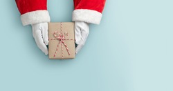 Merry Christmas concept, Top view of Santa claus hands is holding a brown gift box or present box over blue isolated background.