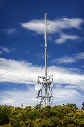 Communication tower radio mast with antenna aerial  against a background of the blue sky.