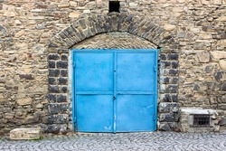 stone wall with arch and blue metall door