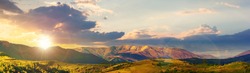 mountainous rural panorama landscape in springtime at sunset. beautiful scenery beneath a sky with clouds in evening light. grass covered hill rolling in to the distant ridge