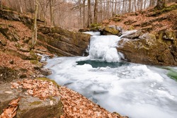 frozen cascade of a forest brook out of the rock. frosty but snowless winter scenery of carpathian primeval beech woods