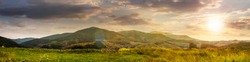 Summer landscape panoramic image of rural fields in mountains under cloudy sky in evening light