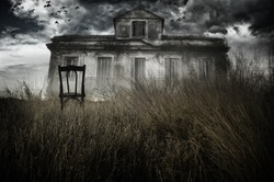 Abandoned chair out in a field facing a haunted house