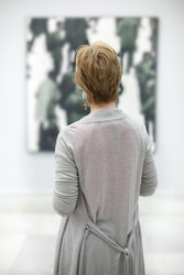 Woman from behind contemplating a pictorial work in a museum in Valencia, Spain
