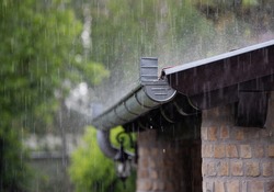 Heavy rain falling on the roof and metal gutter of brick house in summer season