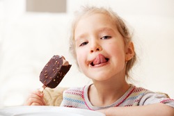 Child eating ice cream. Little girl at home