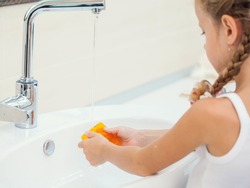 Child washes his hands at bathroom. Girl washing hand with soap