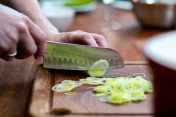 Hands with knife cutting a leek. Ingredients preparation concept.
