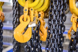 New chain cargo sling. Black steel chain and yellow cargo hooks. Abstract industrial background.