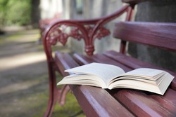 An open book on a park bench seat.