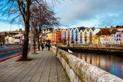 Bank of the river Lee in Cork, Ireland city center with various shops, bars and restaurants. People walking at the street of third largest city in country