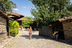 Summer landmark photo of old and authentic bulgarian Zheravna village. Young beautiful woman in floral dress in Bulgaria.
