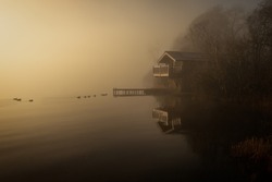 A misty sunrise image of a boathouse in the Lake District, United Kingdom