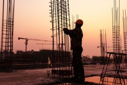 worker working with concrete iron near sunset