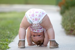 One-year baby girl playing upside down on the street