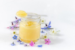 Raw organic royal jelly in a small bottle with litte spoon on small bottle on white