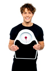 Attractive athlete showing weighing scale against white background