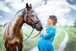 young pregnant woman with a brown horse in the field