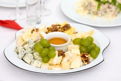 Cheese plate with nuts and honey on restaurant table