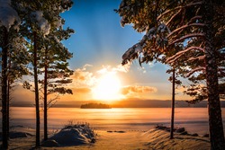 Sunset in Sweden with a lake and pine trees in the foreground