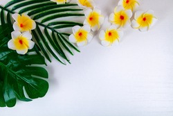 Tropical flowers and leaves on a white wooden background. Vacation in the south.