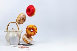 Flying donuts and tea on a white background. Tasty breakfast.