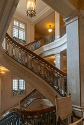 French Renaissance-style 1900s winding spiral staircase with ornate wooden railings and marble stairs.