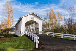 Weddle Wooden Covered Bridge in Sweet Home Oregon in Autumn with Yellow, Golden Trees and Blue Sky and Clouds.