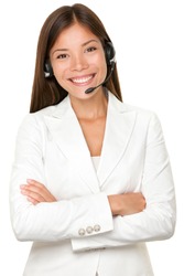 Beautiful cheerful young Asian call operator, receptionist or personal assistant wearing a headset and microphone standing with her arms folded isolated on white