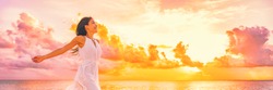 Wellbeing freedom happy woman jumping dancing of joy with open arms in the air blissful banner. Asian woman in sunset clouds pink sky background.