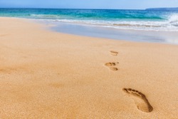 Beach background footprints in sand footprint closeup concept for travel vacation - footsteps in sand on summer tropical getaway holidays vacation with blue ocean . From Maui, Hawaii, USA.