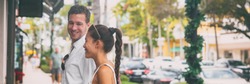 Happy interracial couple talking walking on city street shopping banner panorama. Young man and Asian woman looking at store window together, Naples, Florida, USA travel vacation panoramic.