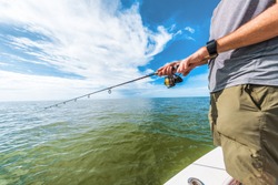 Fishing rod wheel man fishing from fisherman boat in Florida. Wearing smartwatch wearable technology for outdoor sport.