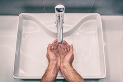 Washing hands with soap at work bathroom sink man hand care hygiene for coronavirus outbreak prevention. Corona Virus pandemic precaution by washing hands frequently for 20 seconds.