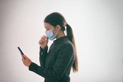 COVID-19 contact tracing app on mobile phone woman walking outside while wearing surgical medical mask touching her face texting smartphone, Coronavirus prevention with geolocation tracking app.