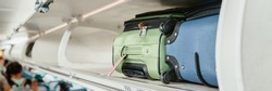 Carry-on luggages in overhead compartment of plane for international flights. Travel restrictions during coronavirus not allowing hand baggage inside airplane.