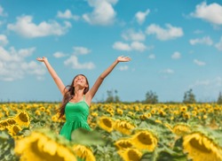 Happy summer woman feeling freedom dancing with arms up to the sky in sunflowers field celebrating fresh clean air breathing allergy free relaxing in the sun. Girl enjoying nature, purifier concept.