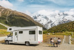 Motorhome camper van RV road trip on New Zealand. Couple on travel vacation adventure. Tourists looking at view of Aoraki Mount Cook National park and mountains on pit stop next to their rental car