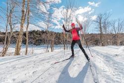 Man Cross Country Skate Skiing Style - Nordic Ski in Forest. Man in winter doing fun endurance winter sport activity in the snow on cross country ski in beautiful nature landscape.