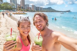 Healthy food happy fit young couple drinking green smoothie juice breakfast running on Waikiki Beach, Honolulu, Hawaii travel vacation. Summer lifestyle active people