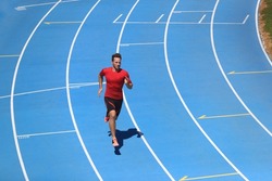 Running man professional athlete runner working out on track and field sport stadium. Top view of male sports person training hiit workout in compression clothes.