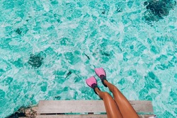 Woman swim feet snorkeler playful having fun with pink snorkel fins over ocean beach. Legs closeup of swimmer relaxing on sea background, Happy vacation travel to tropical vacations