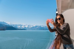 Alaska Glacier bay cruise ship travel tourist looking at icebergs taking pictures using phone in inside passage from balcony deck. Scenic cruising vacation destination panoramic banner