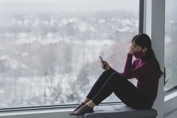 Phone use sad woman wearing mask alone at home during coronavirus. Depression, addiction to social media, anxiety, depression, grief mental heatlh concepts