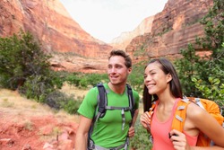 Hiking people - hiker couple on hike outdoors enjoying active lifestyle in beautiful mountain landscape in Zion National Park. Multiracial Asian woman and Caucasian man in Utah, USA.
